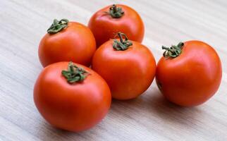 Red tomato on plain wooden table, essential vegetables for all essential foods, view of unpeeled vegetables with plain background photo