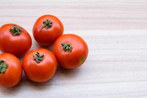 Red tomato on plain wooden table, essential vegetables for all essential foods, view of unpeeled vegetables with plain background photo