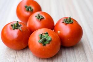Red tomato on plain wooden table, essential vegetables for all essential foods, view of unpeeled vegetables with plain background photo