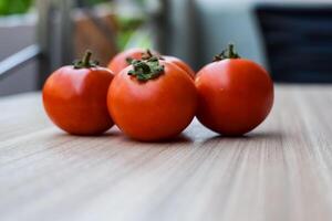 Red tomato on plain wooden table, essential vegetables for all essential foods, view of unpeeled vegetables with plain background photo