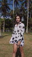 jung Brünette Mädchen auf das Hintergrund von Palme Bäume im ein Kleid. video