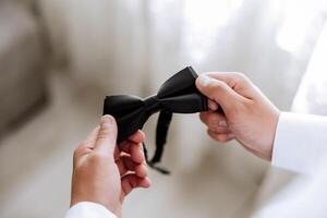 man's tie in hands, close-up photo of hands. The groom is preparing for the ceremony. Last preparations.