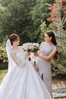 Group portrait of the bride and bridesmaids. A bride in a wedding dress and a bridesmaid in a silver dress hold a stylish bouquet on their wedding day. photo