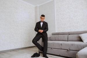 The groom prepares for the wedding ceremony in the morning in his room. Groom's morning. Preparation for the groom's morning. The groom put on a jacket. The confident look of a mature man. photo