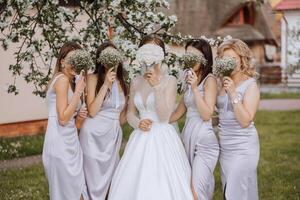 grupo retrato de el novia y damas de honor un novia en un Boda vestir y damas de honor en plata vestidos sostener elegante ramos de flores en su Boda día. foto