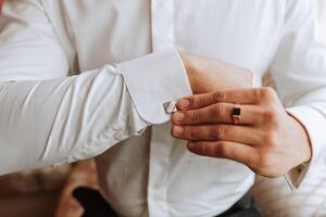 hermoso negocio hombre abotonarse camisa mangas a hogar. el novio es preparando para el boda. de cerca foto. foto
