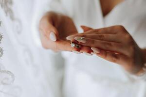 Close-up of an elegant diamond ring on a woman's finger with a modern manicure, sunlight. Love and wedding concept. Soft and selective focus. photo