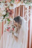 a brunette bride in a tiara poses with a bouquet of white and pink flowers. Beautiful hair and makeup. Spring wedding photo