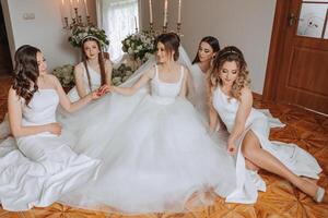 Friends rejoice with the bride in the morning. They take pictures, smile, help the bride fasten her dress. photo