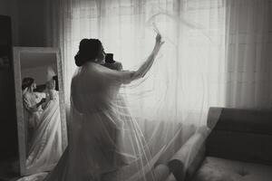 portrait of a luxurious bride in boudoir style near a mirror with reflection. Preparing the bride for the wedding in the morning in a white robe. photo