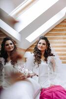 portrait of a luxurious bride in boudoir style near a mirror with reflection. Preparing the bride for the wedding in the morning in a white robe. photo