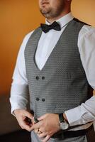 The groom fastens a button on his vest at the groom's morning gatherings. Groom wedding preparation. photo