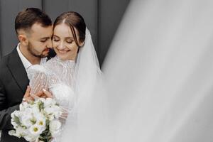 el hermosa novia suavemente abrazos el acicalar, quien abrazos su por el espalda. Boda concepto. el belleza y sensibilidad de un hombre y un mujer foto