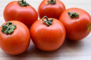 Red tomato on plain wooden table, essential vegetables for all essential foods, view of unpeeled vegetables with plain background photo