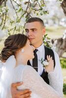 Wedding. Love and couple in garden for wedding. Celebration of ceremony and commitment. Save the date. Trust. The bride and groom embrace. The groom embraces the bride under a spring flowering tree. photo