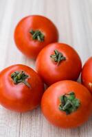 Red tomato on plain wooden table, essential vegetables for all essential foods, view of unpeeled vegetables with plain background photo