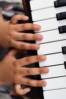 asiático linda niña jugando el sintetizador o piano. linda pequeño niño aprendizaje cómo a jugar piano. niño manos en el teclado interior. foto
