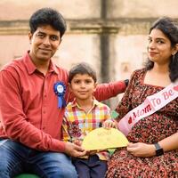 Indian couple posing for maternity baby shoot with their 5 year old kid. The couple is posing in a lawn with green grass and the woman is flaunting her baby bump in Lodhi Garden in New Delhi, India photo