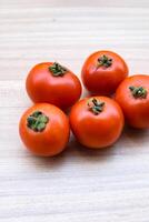 Red tomato on plain wooden table, essential vegetables for all essential foods, view of unpeeled vegetables with plain background photo
