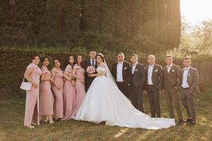 full-length portrait of the newlyweds and their friends at the wedding. The bride and groom with bridesmaids and friends of the groom are having fun and rejoicing at the wedding. photo