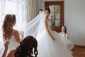 Friends rejoice with the bride in the morning. They take pictures, smile, help the bride fasten her dress. photo