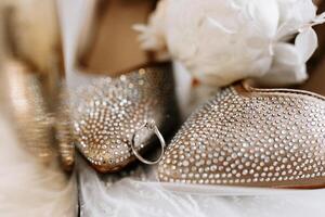 The bride's engagement ring, fashionable stilettos, fresh rose flowers. Wedding details in golden style. photo