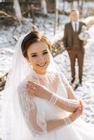 Wedding portrait of the bride and groom. Winter walk in nature. The bride stands in front of the groom. photo