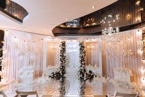 The wedding table of the bride and groom, decorated with flowers, white tulle, made in light pink color. Flowers on stands. Wedding details. Light photo