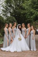 grupo retrato de el novia y damas de honor un novia en un Boda vestir y damas de honor en plata vestidos sostener elegante ramos de flores en su Boda día. foto