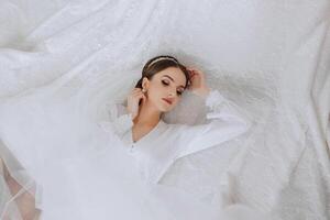 A beautiful brunette bride with a tiara in her hair is getting ready for the wedding in a beautiful robe in boudoir style. Close-up wedding portrait, photo. photo