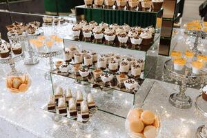 Candy bar for a wedding. Candy bar standing festive table with desserts, cupcakes and macarons. Beautiful and tasty. photo