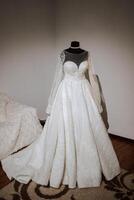 Bedroom interior with wedding dress prepared for the ceremony. A beautiful lush wedding dress on a mannequin in a hotel room. photo