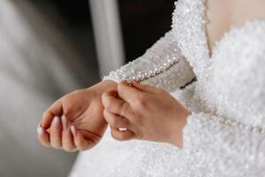 The bride fastens the sleeve of her wedding dress. Morning of the bride. Preparation. Wedding photography photo