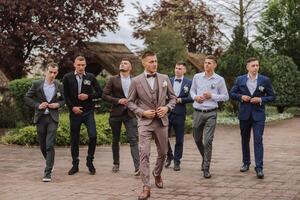 Cheerful, young, energetic witnesses of the groom next to the groom. Friends congratulate the groom. Groom and his funny friends having fun on the wedding day of the newlyweds. photo