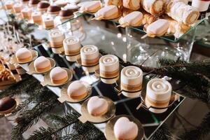 un delicioso boda. blanco pastel decorado con flores caramelo bar para un banquete. celebracion concepto. de moda postres mesa con dulces, dulces. frutas foto