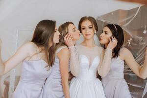 Friends rejoice with the bride in the morning. They take pictures, smile, help the bride fasten her dress. photo