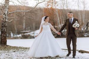 The bride and groom are walking in the winter garden. Winter photo session in nature.