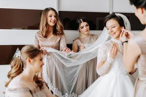 The bridesmaids help the bride get dressed. Preparation for the wedding. Morning of the bride photo