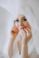 A beautiful brunette bride with a tiara in her hair is getting ready for the wedding in a beautiful robe in boudoir style. Close-up wedding portrait, photo. photo