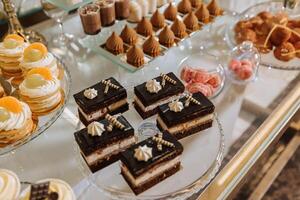 un delicioso boda. pastelitos, pasteles caramelo bar para un banquete. celebracion concepto. de moda postres mesa con dulces, dulces. frutas foto