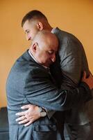 A father hugs his mature son and helps him prepare for the wedding ceremony. Warm and sincere relations between a father and an adult son. An emotional moment at a wedding photo