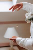 Playful excited young groom throwing wedding ring. Close-up photo of hands throwing wedding rings. High quality photo