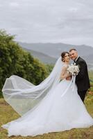 Wedding. Love and couple in garden for wedding. Celebration of ceremony and commitment. Save the date. Trust The groom embraces the bride in the mountains on the background of the forest photo