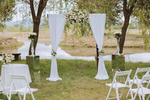 White arch and white chairs in the forest for a wedding ceremony. Preparation. Wedding in nature photo