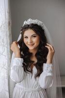 A beautiful brunette bride with a tiara in her hair is getting ready for the wedding in a beautiful robe in boudoir style. Close-up wedding portrait, photo. photo