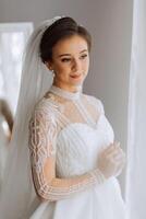 Moda retrato de un hermosa novia en un lujoso Boda vestir con cordón y cristales en un Arábica interior estilo. hermosa novia con un ramo de flores de flores preparación para el Boda ceremonia. foto