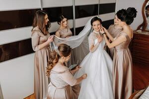 The bridesmaids help the bride get dressed. Preparation for the wedding. Morning of the bride photo