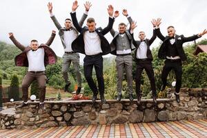 Cheerful, young, energetic witnesses of the groom next to the groom. Friends congratulate the groom. Groom and his funny friends having fun on the wedding day of the newlyweds. photo