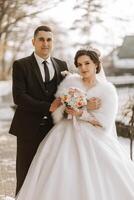 invierno boda. contento Pareja caminando en Boda ropa abrazando y sonriente en un invierno parque cubierto con nieve en su Boda día. invierno amor historia de un hermosa Pareja en Nevado invierno clima foto