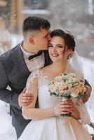 Happy couple kissing in winter. Couple embracing in snowy winter park.Winter wedding of stylish beautiful young couple bride and groom photo